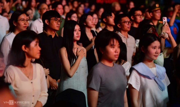Hàng nghìn khán giả - người đặt tay lên ngực, người giơ tay chào cờ - hát quốc ca cùng ca sĩ, tạo không khí hào hùng.