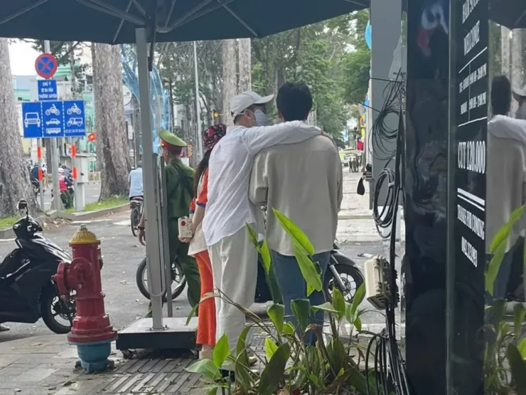 Hình ảnh ca sĩ Lâm Chấn Huy (đeo khẩu trang) khoác vai một người đàn ông trước trụ sở Công an TP.HCM.
